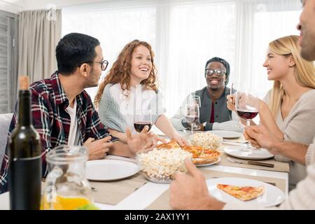 Multi-ethnic group of five friends relaxing at dinner table together at weekend, horizontal shot Stock Photo