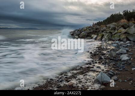 Stormy morning along a rocky beach with dramatic waves hitting rocks. Stock Photo