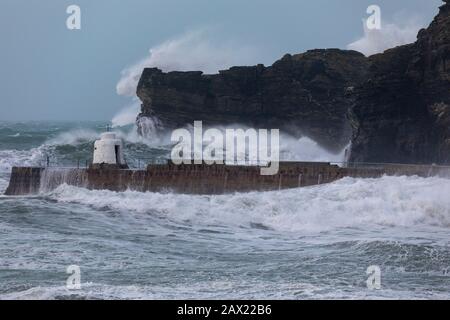 Storm Ciara batters the Cornish coast with giant waves as tall as the surrounding cliffs crashing against the breakwater Stock Photo