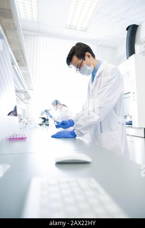 Vertical shot of two unrecognizable doctors in white coats working in modern laboratory examining specimens Stock Photo