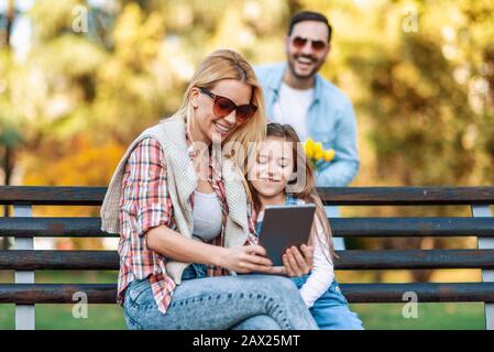 Happy family of three having fun together outdoor.Family,lifestyle and technology concept.Spring day in the park. Stock Photo