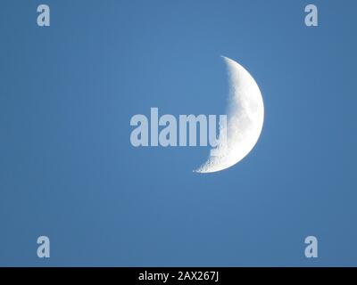 Waxing quarter moon at dusk twilight with craters mountains and maria visible Stock Photo