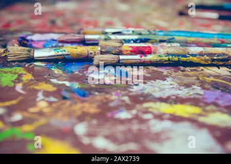 Old oil painting brushes on stained wooden palette Stock Photo