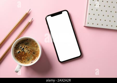 Phone with empty screen, copybook, pencils and cup of coffee on pink background, top view Stock Photo