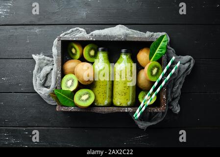 Green Smoothies with fresh kiwi and kiwi on a black background Wooden. Rustic style. Fruits. Top view. Free space for text. Stock Photo