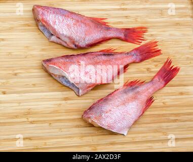 Fresh raw red fish on wooden cutting board. Raw red sea perches. Fish wooden chopping board. Stock Photo