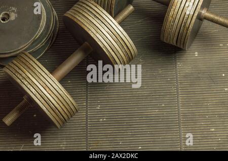 Old Iron Rusty Dumbbells and Additional Plates on scratched rubber floor Stock Photo