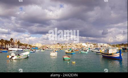 MARSAXLOKK, MALTA. Maltese 'Luzzu' -  brightly-coloured traditional fishing boats still used today in villages such as Marsaxlokk - floating in Marsax Stock Photo