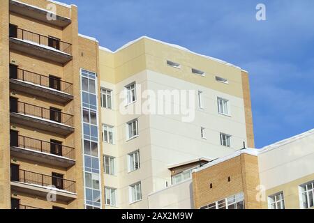 Plastic windows in a modern tiled brick high-rise house on blue sky background. Bottom view. Stock photo modern urban development for web and print. Stock Photo