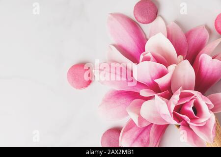 Beautiful spring pink magnolia flowers with macaroons on white table with copy space for your text. top view. flat lay. wedding or womens day backgrou Stock Photo