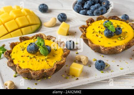 Vegan food dessert. raw vegan yellow mango cakes with fresh blueberries and mint. healthy delicious gluten free food. close up
