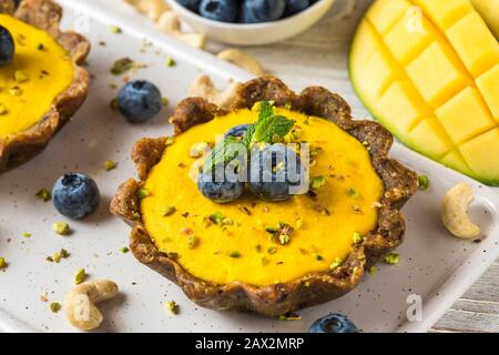homemade raw mango cakes with fresh berries, pistachio and mint. healthy vegan gluten free food concept. close up Stock Photo