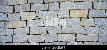 stone wall made from dry piled up broken granite stones Stock Photo