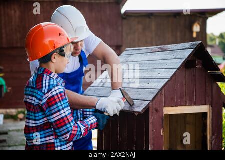 Young teenager boy learns to hammer nails with his father. outdoors in the village Stock Photo