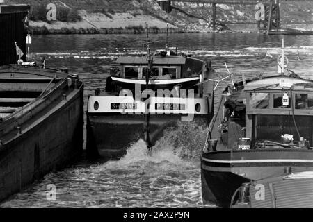 AJAXNETPHOTO. SEPTEMBER, 1971. AMFREVILLE, FRANCE. - TIGHT SQUEEZE - THE FREYCINET PENICHE STE.ANNE, HER PROPELLOR THRASHING, LEAVES THE LOCK AT AMFREVILLE NEAR POSES ON THE RIVER SEINE AS OTHER BARGES WAIT TO GET UNDER WAY. PHOTO:JONATHAN EASTLAND/AJAX REF:RX7 151204 147 Stock Photo