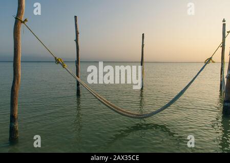 Relaxing in a hammock over the water on sunset, Isla Holbox, Mexico Stock Photo