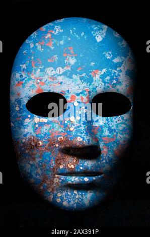 Textured mask with cracked rough wood  painted surface, neutral expression on dark background. Stock Photo