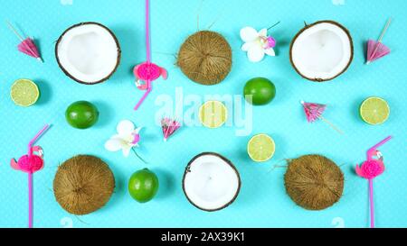 Coconut summertime theme flat lay creative layout overhead with drinking, straws, coconuts and limes on modern blue background. Stock Photo