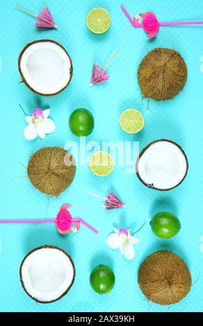 Coconut summertime theme flat lay creative layout overhead with drinking, straws, coconuts and limes on modern blue background. Stock Photo