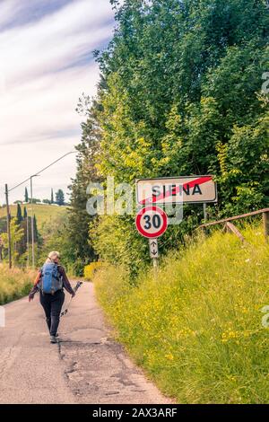Hiker leaving Sienna Tuscany Italy hiking pass the Seina sign Stock Photo