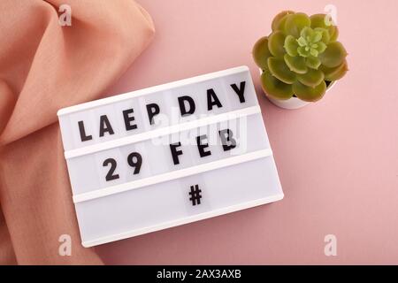 White block calendar present date 29 and month February and plant on pink background. Leap day Stock Photo