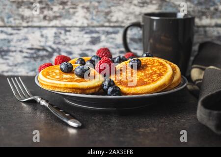 Sweet homemade pancakes with blueberries and raspberries on old kitchen table. Stock Photo