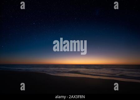 P view of the Milky Way vanishing above the coast line of the Atlantic Ocean, as the sun rises over the horizon in the Southern hemisphere. Stock Photo