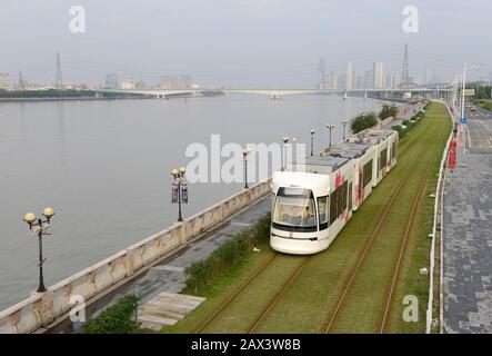 A tram travels by the Pearl river on the Haizhu tram system in Guangzhou, China Stock Photo