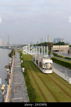 A tram travels by the Pearl river on the Haizhu tram system in Guangzhou, China Stock Photo