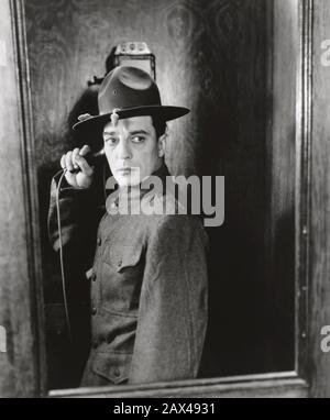 1930 , USA  : The american silent movie actor and director BUSTER KEATON ( 1895 - 1966 ) , in DOUGHBOYS ( 1930 - Il guerriero )  by Edward Sedgwick - SILENT MOVIE - CINEMA MUTO  - portrait - ritratto -  regista cinematografico - attore  - comico   - COMICO - shoes - hat - cappello -  ANNI TRENTA - 30's - '30 -  military uniform - divisa uniforme militare - telephone - phone - telefono a muro ----  ARCHIVIO GBB Stock Photo