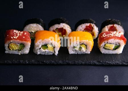 Different types of rolls stand on a black granite board for sushi on a black background Stock Photo