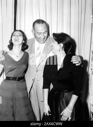 1955 , Hollywood , USA : The italian movie actress ANNA  MAGNANI arrive in USA for his role into the movie THE  ROSE TATTOO ( La rosa tatuata , 1955 ) by  Daniel Mann , from a play by Tennessee Williams . In this photo with the partner MARISA PAVAN and the director DANIEL MANN at the conference for the presentation of project to the international press  before the making of movie. - CINEMA - FILM -  MOVIE - PORTRAIT - RITRATTO - smile - sorriso - risata - satin - raso - black dress - abito vestito nero  ----  Archivio GBB Stock Photo