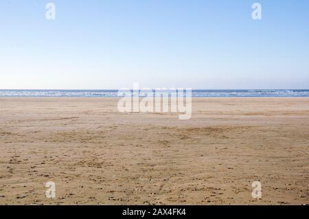 Large empty sandy beach with golden sand leading to the ocean Stock Photo