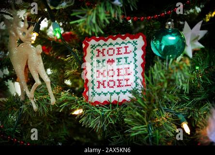 Hand stitched Christmas ornament with the word Noel embroidered on it. Handmade needlepoint Christmas decoration hanging on the tree. Stock Photo