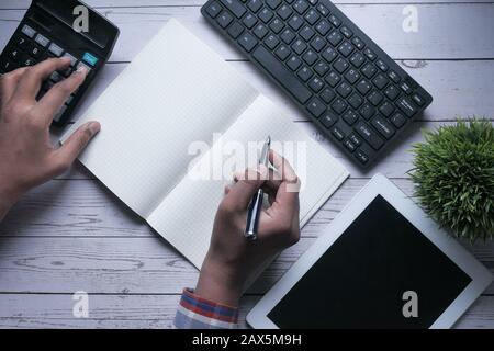 top view of man hand writing on notepad and using calculator  Stock Photo