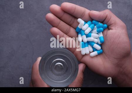 young man hand taking capsule with glass of water  Stock Photo
