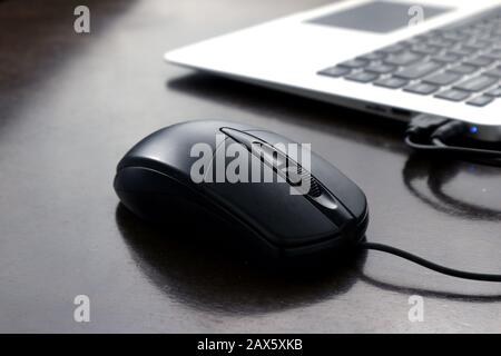 Photo of a computer mouse and laptop computer keyboard on a wooden table. Stock Photo