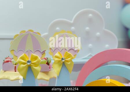 Girl party decoration with rainbow ornaments, clouds, colorful umbrellas in pastel colors. Candy table decoration with beautiful decor. Stock Photo