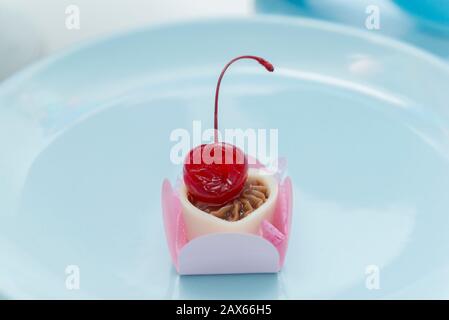 Close up of Tray with chocolate candies topped by a cherry. Wedding decoration table. Selective focus. Luxuriously decorated party table. Stock Photo