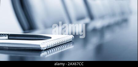 Closeup of notepad kept on table in empty conference room Stock Photo