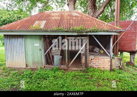 Old colonial style shed in an outdoor backyard after rainfall when the grass and foliage are lush and green Stock Photo