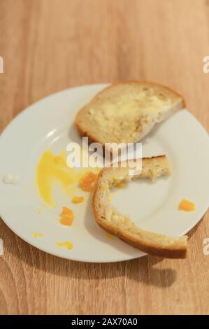 Leftovers from a breakfast meal with a piece of loaf, loaf crust and yolk Stock Photo
