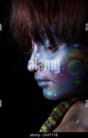 Studio shot of model girl portrait with abstract colorful make-up, face closeup, facing sideways, looking down Stock Photo