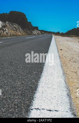 Vertical shot of the white paint on the edges of the road Stock Photo