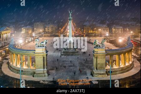 Budapest, Hungary - Aerial view of angel sculpture at Heroes' Square (Hosok tere) with Christmas decorated Andrassy street. Heavy snowing in Budapest Stock Photo