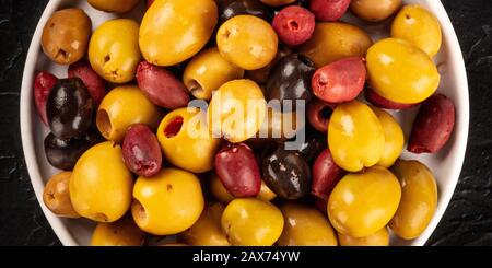 Olives variety close-up panorama. Black, green and red olives, an assortment, shot from above Stock Photo