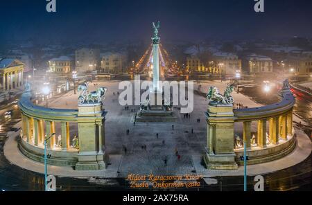 Budapest, Hungary - Aerial view of angel sculpture at Heroes' Square (Hosok tere) with Christmas decorated Andrassy street. Heavy snowing in Budapest Stock Photo