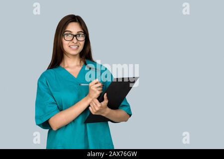 Smiling young indian woman nurse point at copy space isolate on gray background Stock Photo
