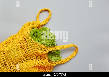 Knitted bag with salad on a gray background with copy space. Shopping food with eco friendly bag. Caring for the environment, rejection of plastic, ze Stock Photo