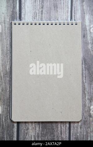 Gray sheet paper from a spiral notebook lies on the background of wooden boards. Stock Photo